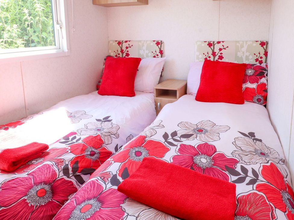 A bedroom with two beds and a window at The Lodge in Amlwch