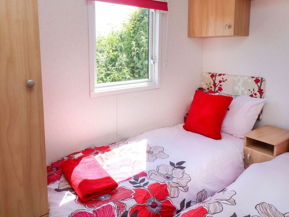 A bedroom with two beds and a window at The Lodge in Amlwch