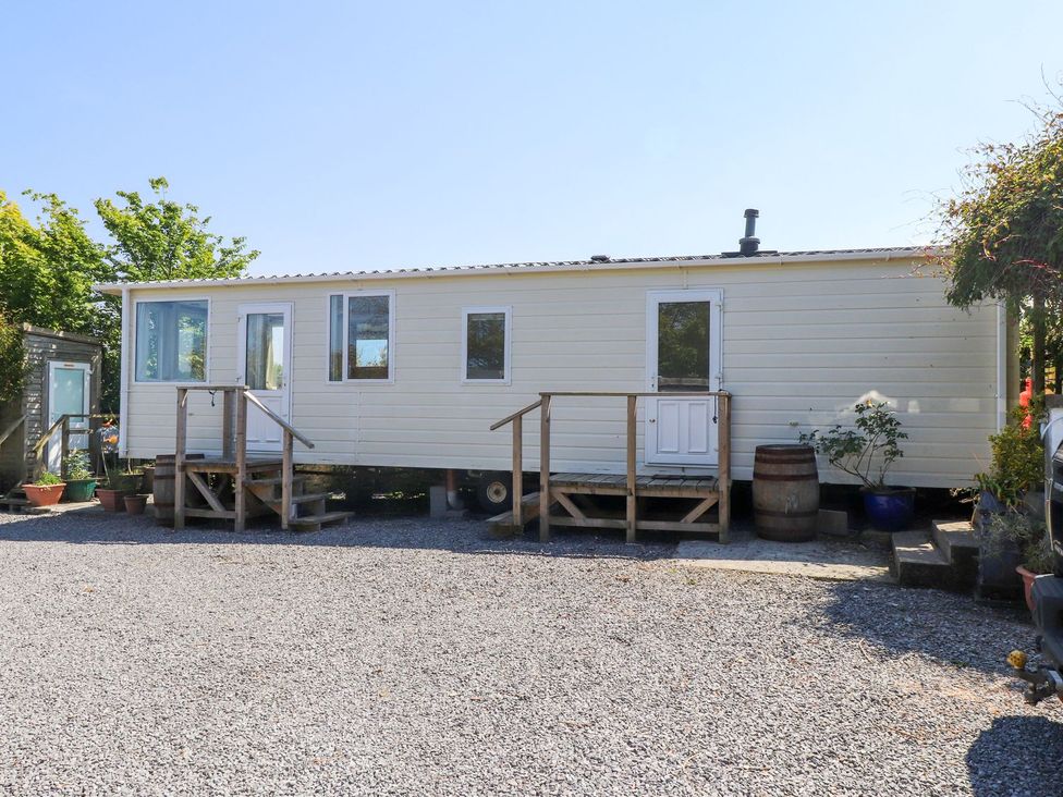 A mobile home with steps and gravel area at The Lodge in Amlwch