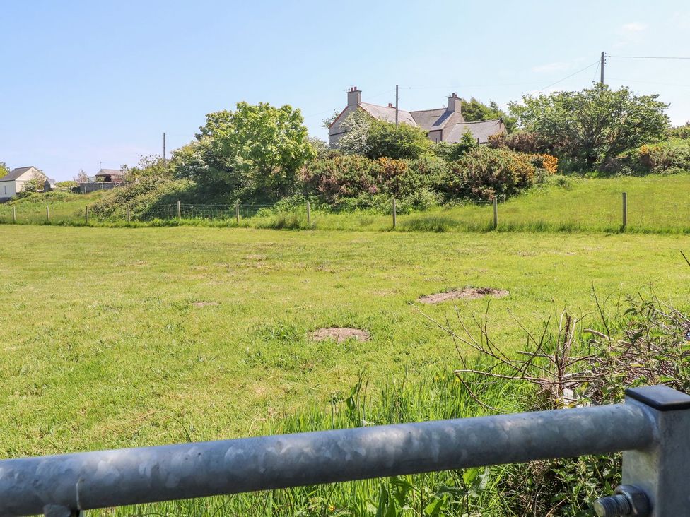 A view of a field with a house and trees at The Lodge in Amlwch