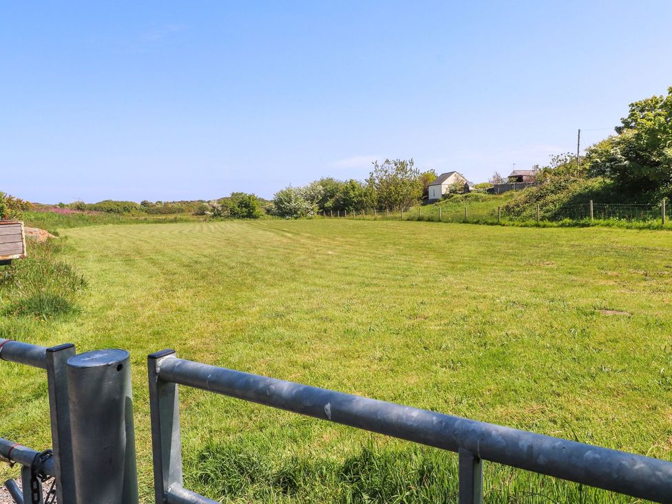 A field with a fence and trees at The Lodge in Amlwch