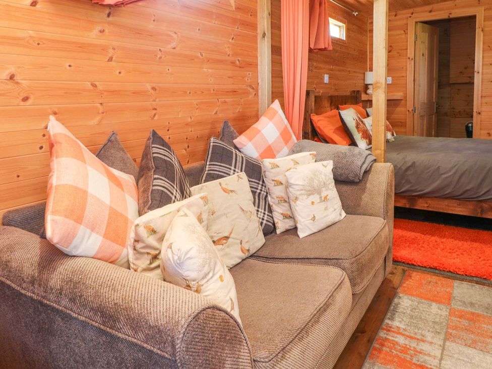 A living room with a sofa and pillows at The Cabin in Amlwch