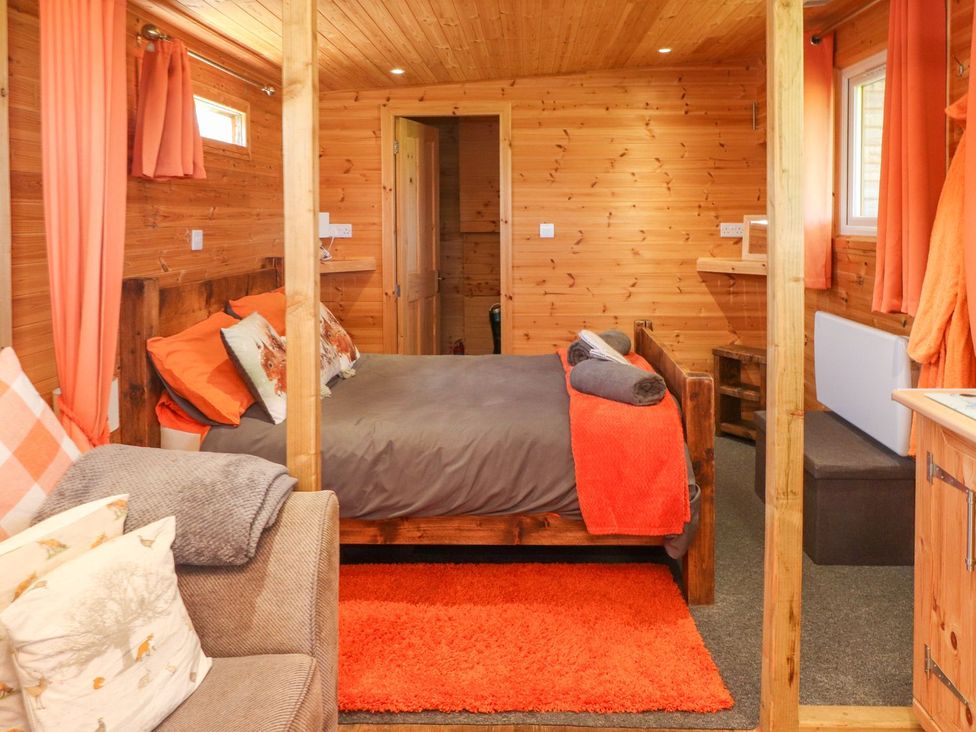 A bedroom with a bed and sofa at The Cabin in Amlwch