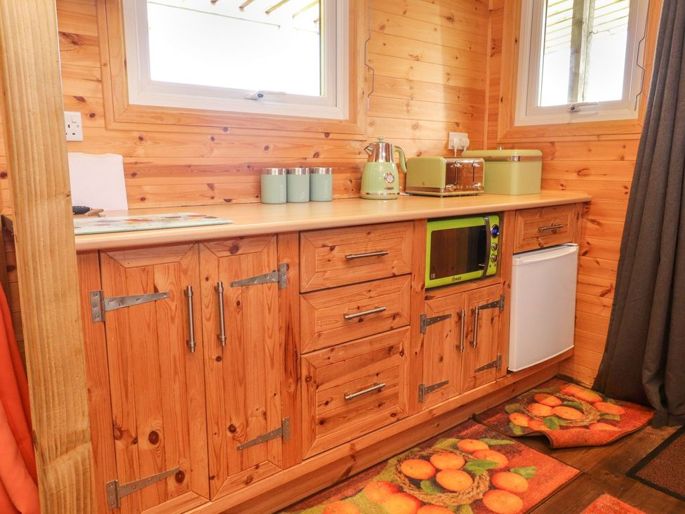A kitchen with cabinets and appliances at The Cabin in Amlwch