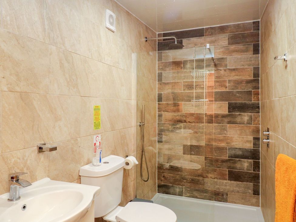 A bathroom featuring a shower, sink, and toilet at The Cabin in Amlwch