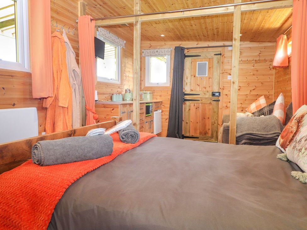 A bedroom with a bed and kitchenette at The Cabin in Amlwch