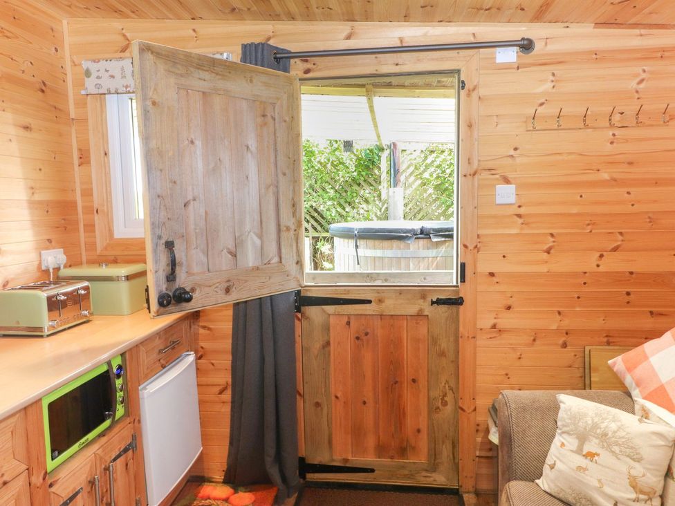A kitchen with a door and window open showing outdoor space at The Cabin in Amlwch
