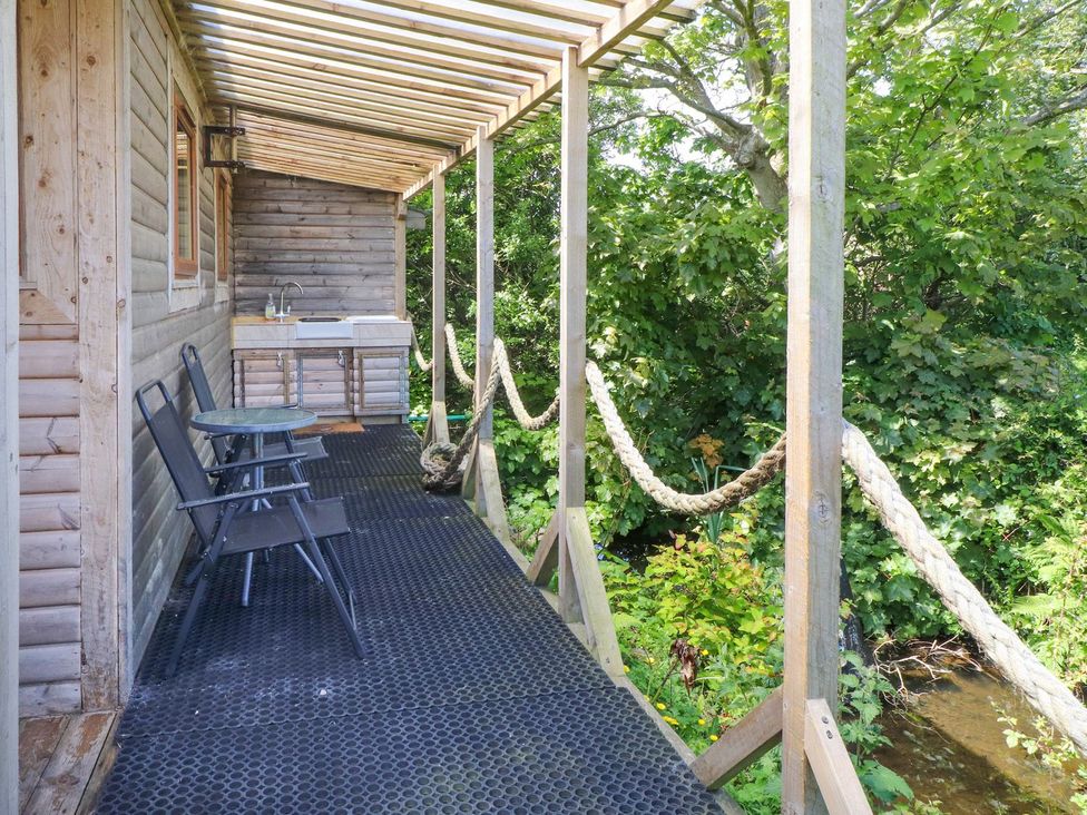 An outdoor area with a deck, chairs, and a kitchen sink at The Cabin in Amlwch