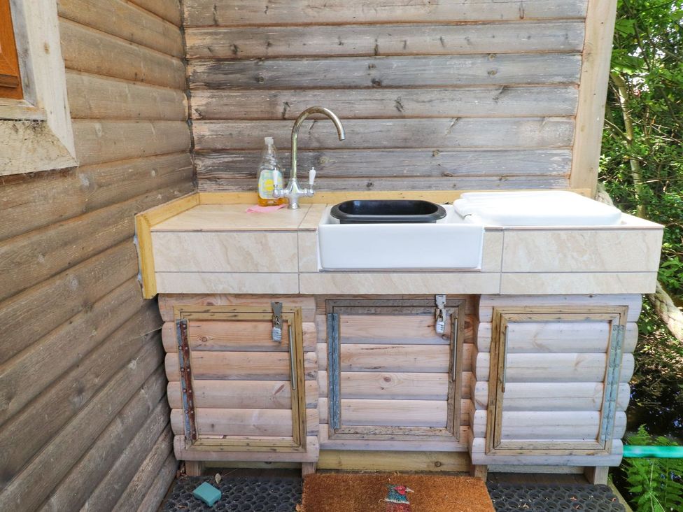 A kitchen area with a sink and cabinets at The Cabin in Amlwch