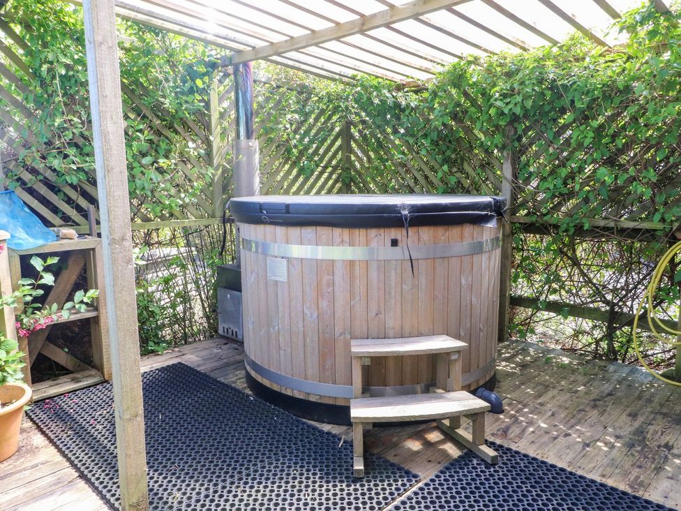 An outdoor area with a hot tub and wooden steps at The Cabin in Amlwch