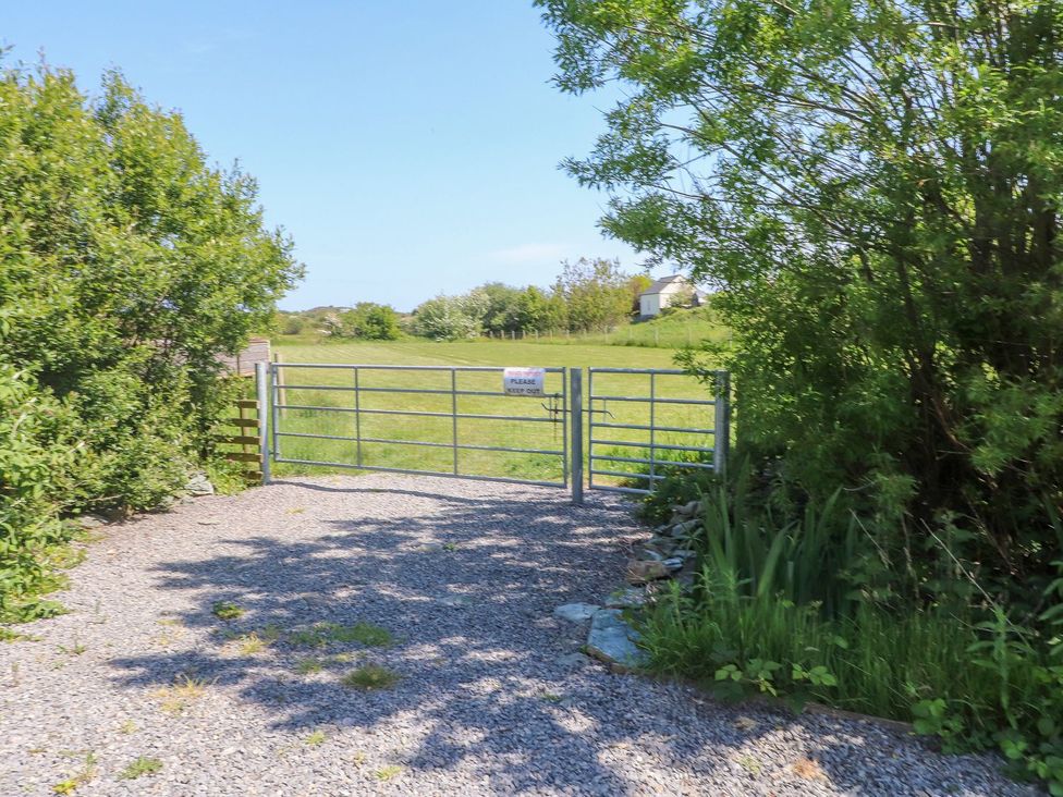 A gate leading to a grassy area at The Cabin in Amlwch
