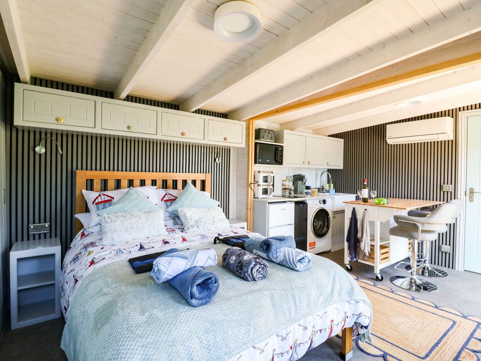 A bedroom with a bed and kitchen appliances at The Cabin in Herne Bay