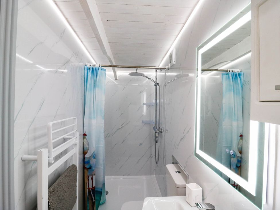A bathroom with a shower, toilet, and sink at The Cabin in Herne Bay