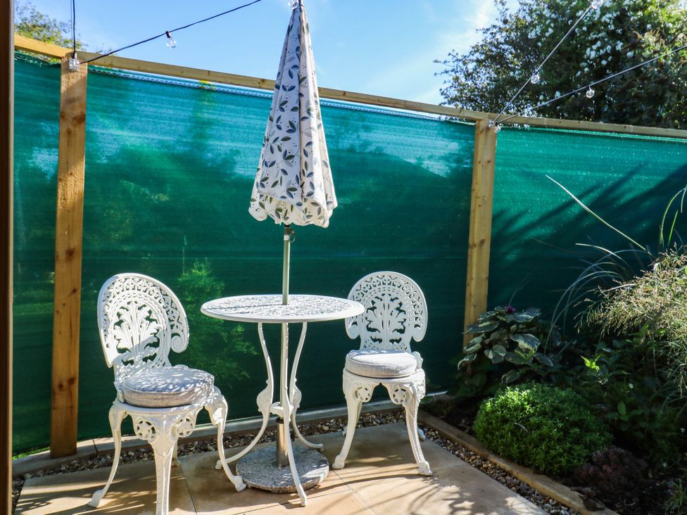 An outdoor area with a table and chairs under an umbrella at The Cabin in Herne Bay