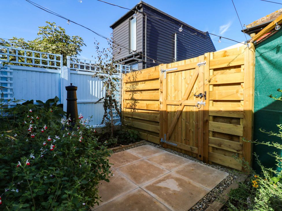 A garden with a wooden gate and paving slabs at The Cabin in Herne Bay