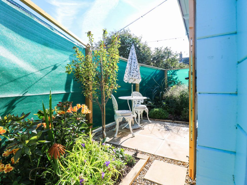 A garden with a table and chairs under an umbrella at The Cabin in Herne Bay
