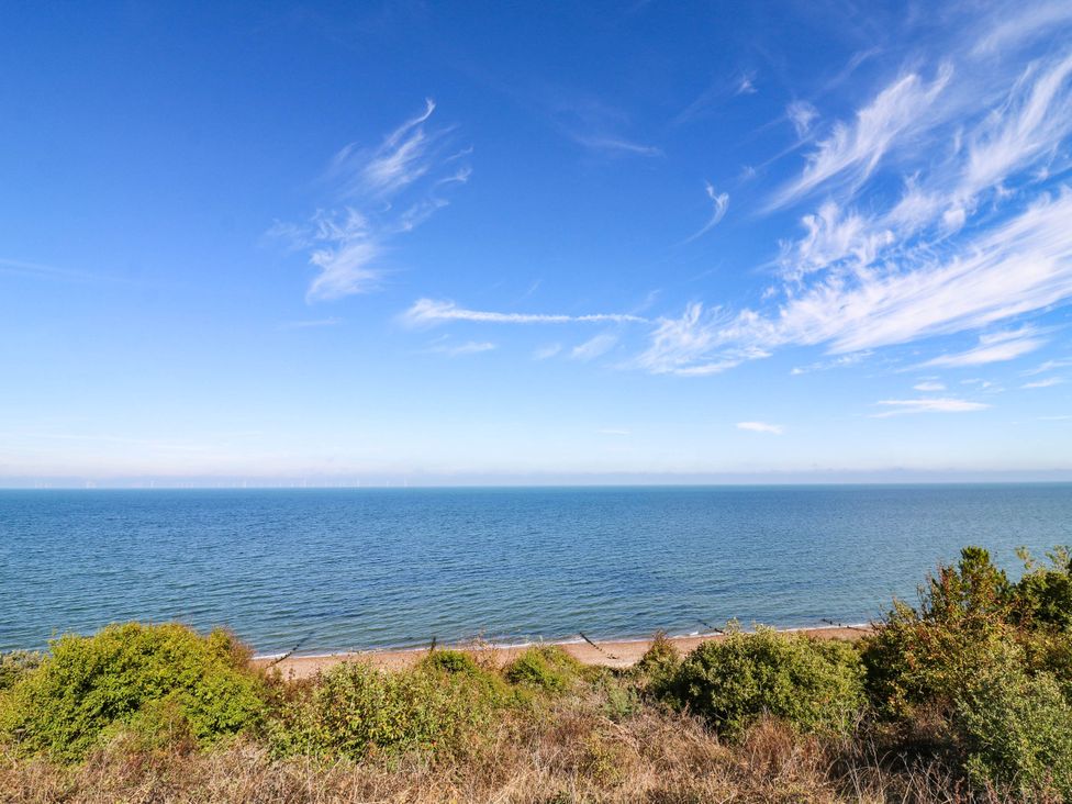 A view of the ocean and beach with vegetation at The Cabin in Herne Bay