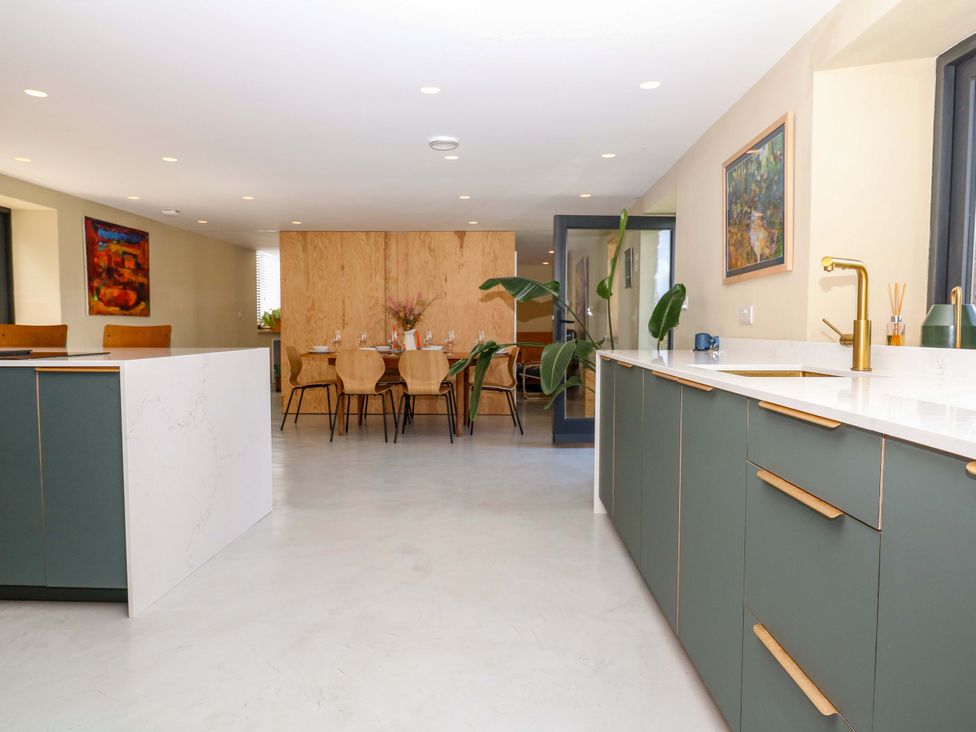 A kitchen with cabinets and a dining area at Reddaway Byre Okehampton