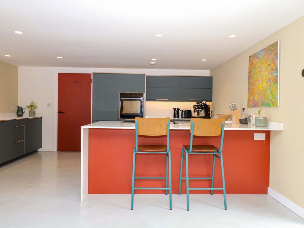 A kitchen with bar stools and appliances at Reddaway Byre Okehampton