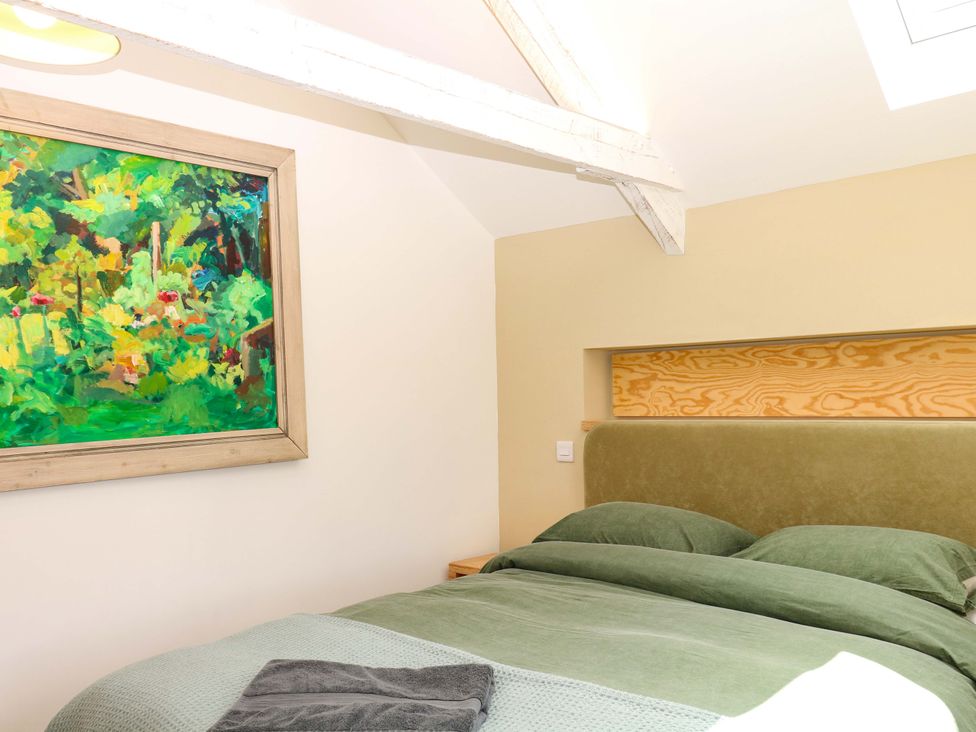 A bedroom with a bed and painting at Reddaway Byre Okehampton