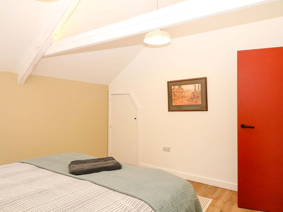 A bedroom with a bed and a red door at Reddaway Byre Okehampton