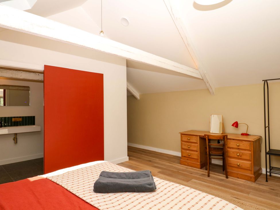 A bedroom with a desk and lamp at Reddaway Byre Okehampton