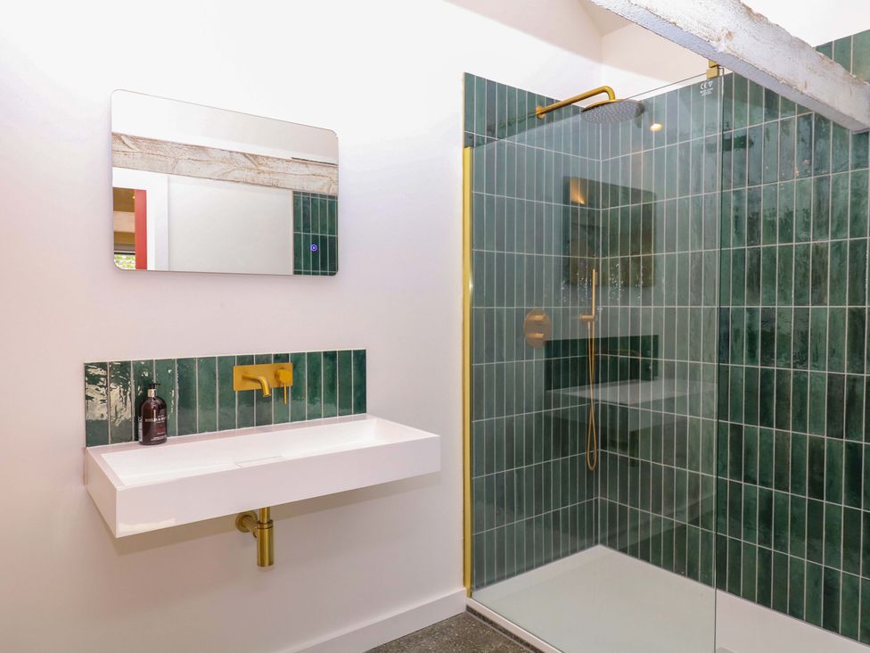 A bathroom with a mirror, sink, and shower at Reddaway Byre in Okehampton