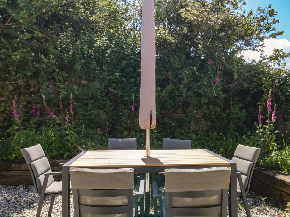 A garden with a table and chairs under an umbrella at Reddaway Byre Okehampton