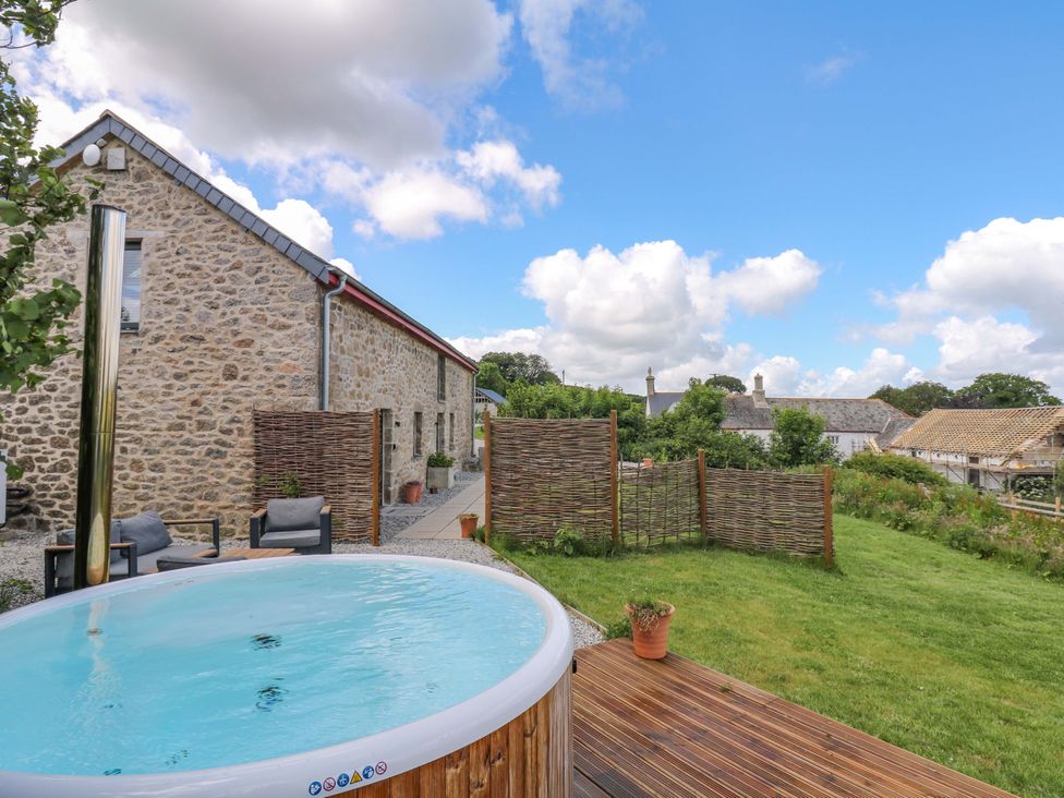 An outdoor area with a hot tub and garden at Reddaway Byre in Okehampton