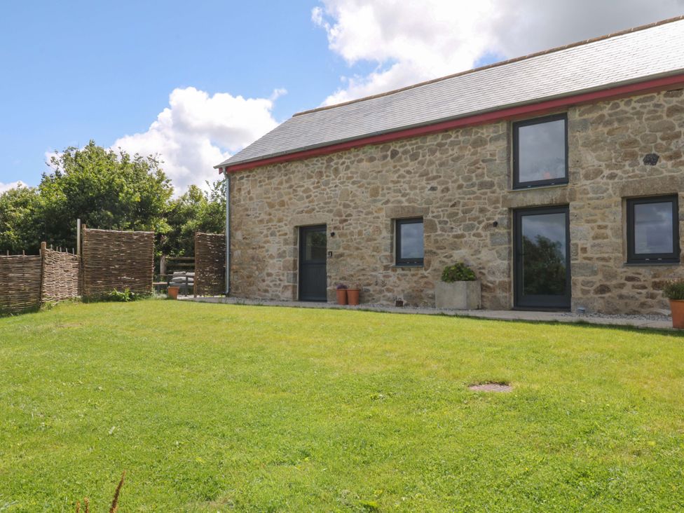 An outdoor view of a stone house with a garden at Reddaway Byre Okehampton