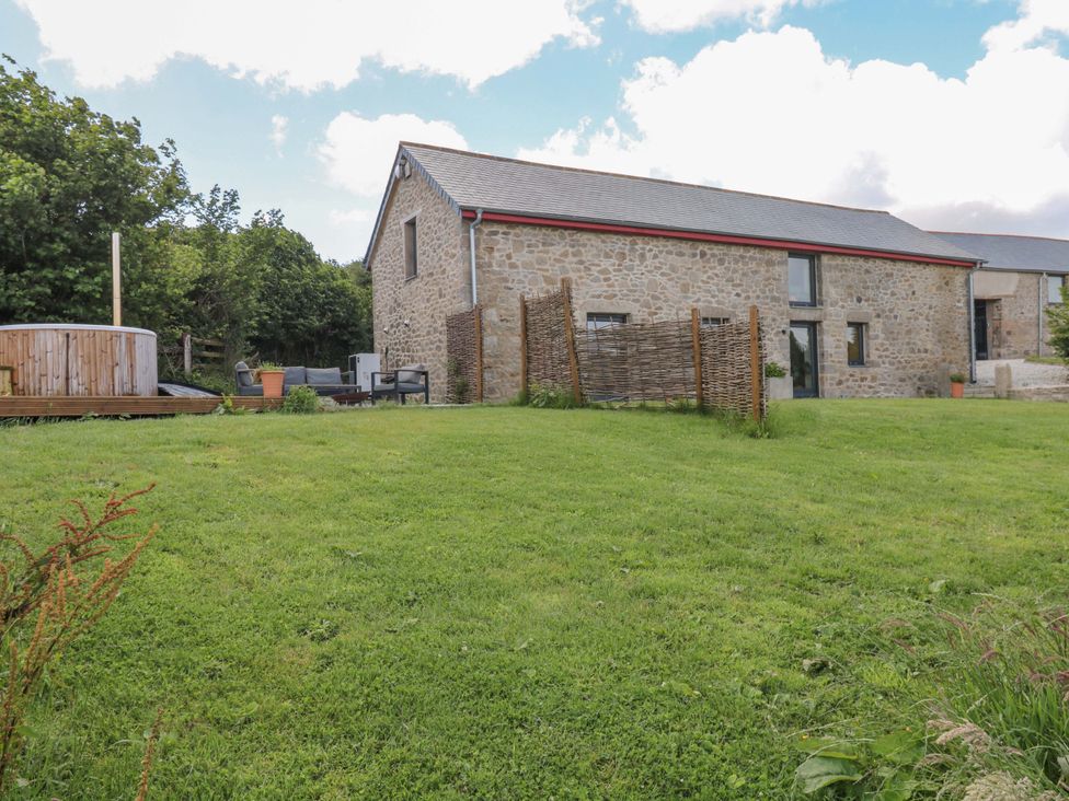 An outdoor view of a house with stone walls and a hot tub at Reddaway Byre Okehampton