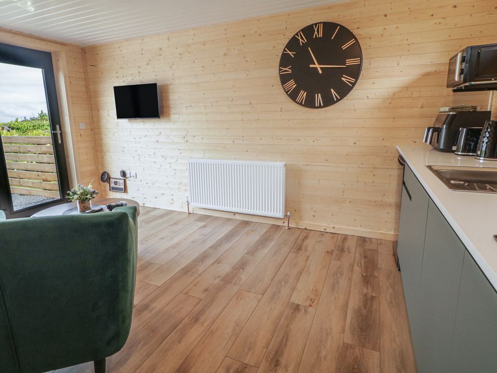 A room with a clock, television, and kitchen elements at Alken The Stag, Bushmills, County Antrim