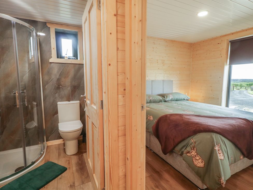 A bedroom with a bed and attached shower room at Alken The Stag in Bushmills, County Antrim