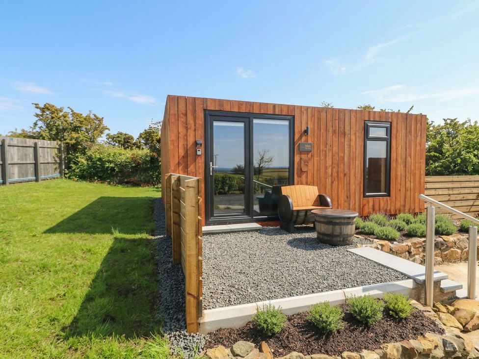 A wooden cabin with a gravel path and plants at Alken The Stag in Bushmills, County Antrim