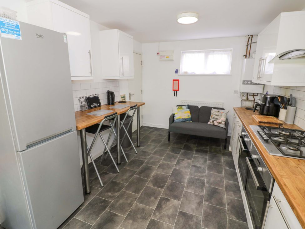 A kitchen with refrigerator, stove, and seating area at 9 Uist Walk in Corby