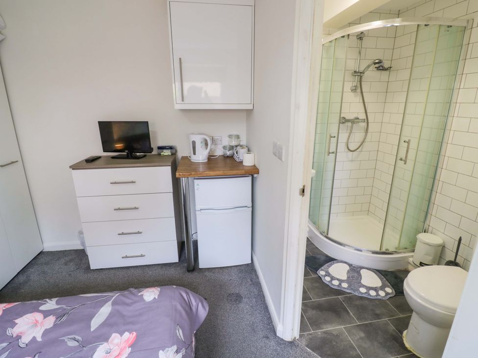 A bedroom with a bed, television, fridge, and shower at 9 Uist Walk Corby
