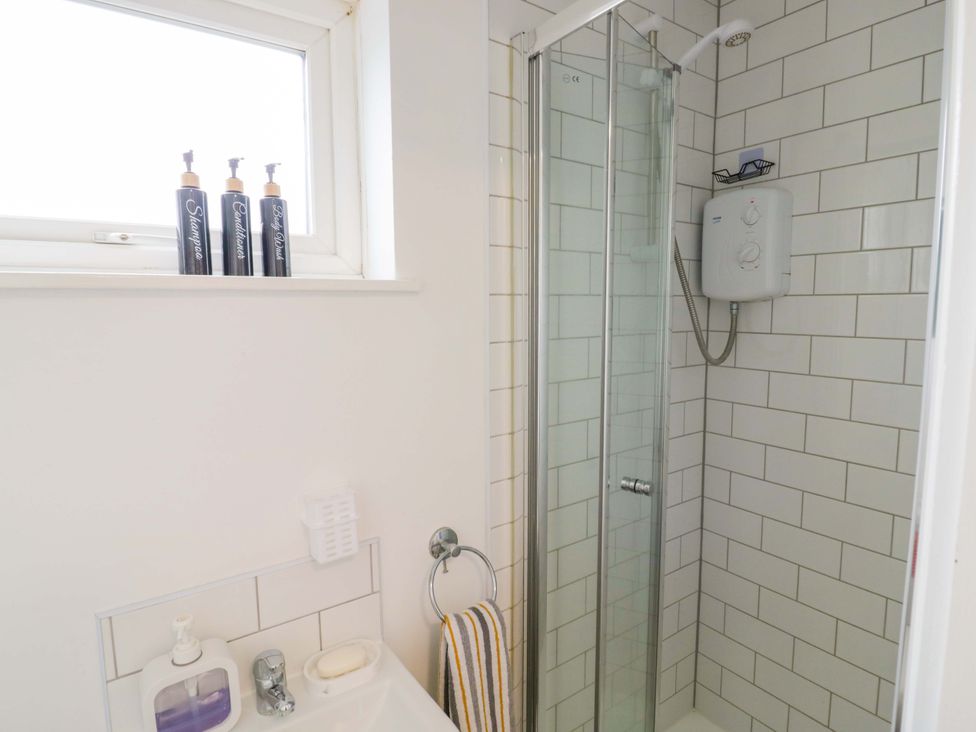 A bathroom with a shower and soap dispenser at 9 Uist Walk Corby