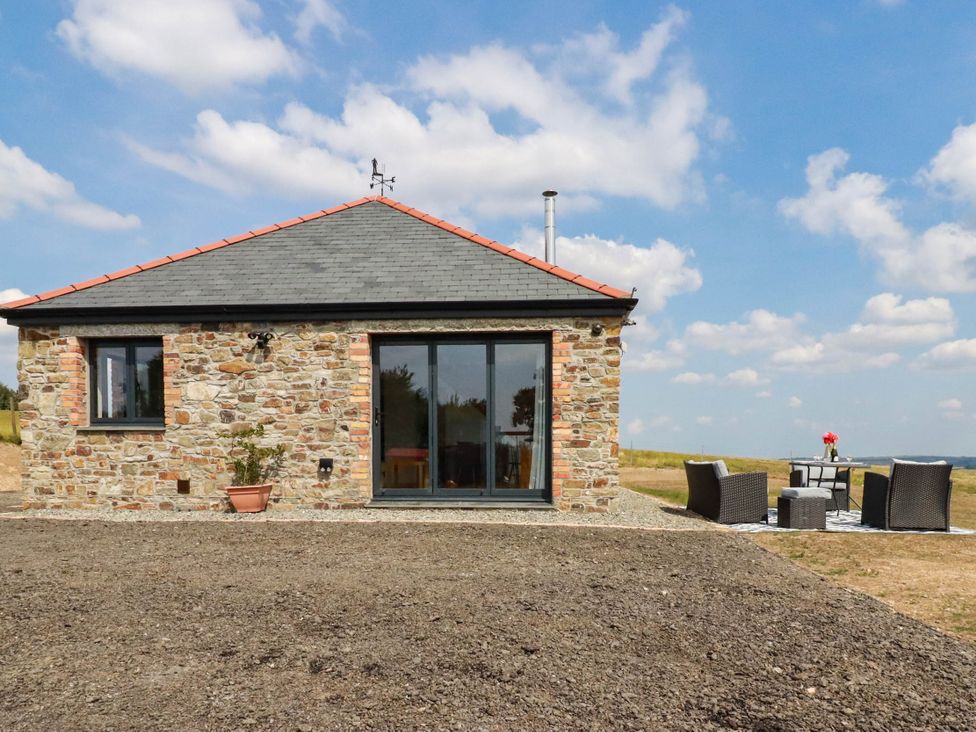 A stone house with a slate roof and outdoor seating area at The Granary in Launceston