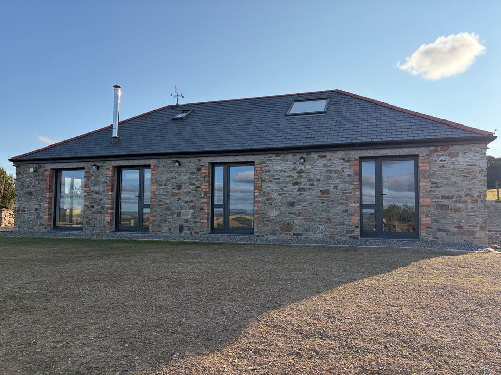 A stone building with multiple windows and a chimney at High View Barn in Launceston