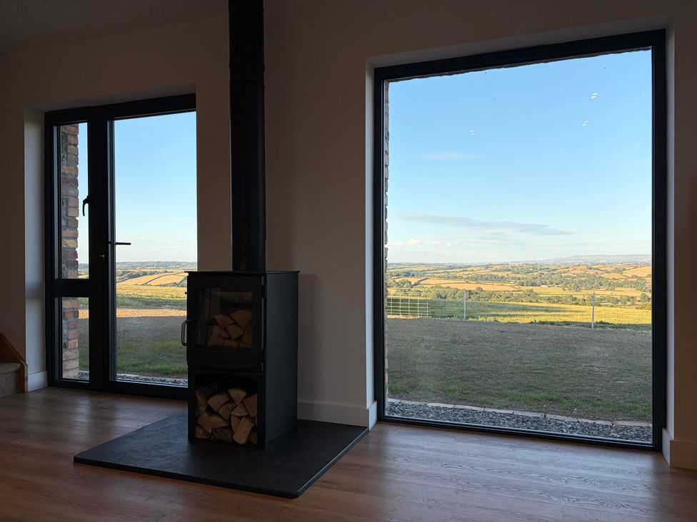 A living room with a wood stove and large windows at High View Barn Launceston