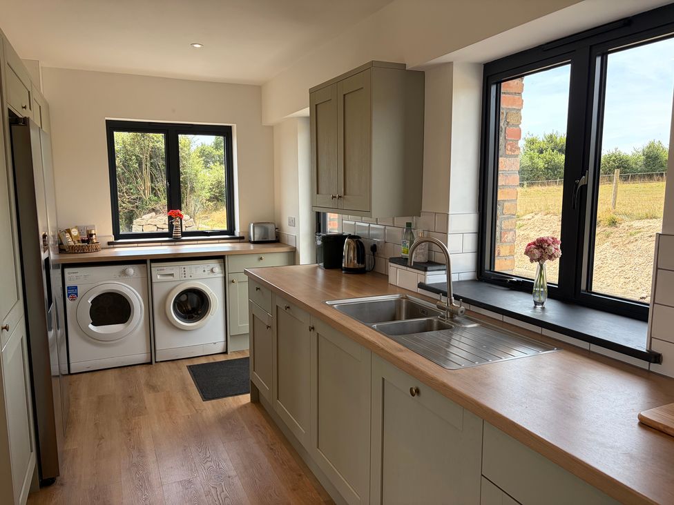 A kitchen with a sink, washing machine, and window at High View Barn in Launceston