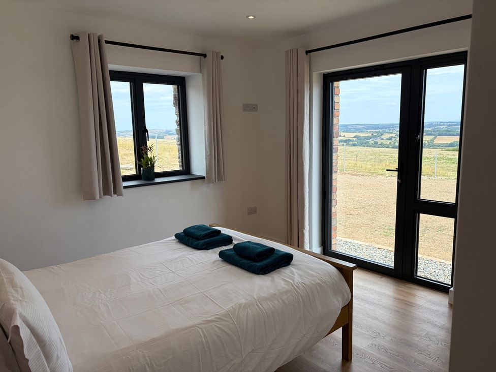A bedroom with a bed and windows overlooking a landscape at High View Barn in Launceston