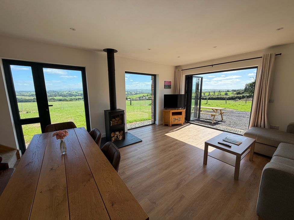 A living room with a dining table and a television at High View Barn in Launceston
