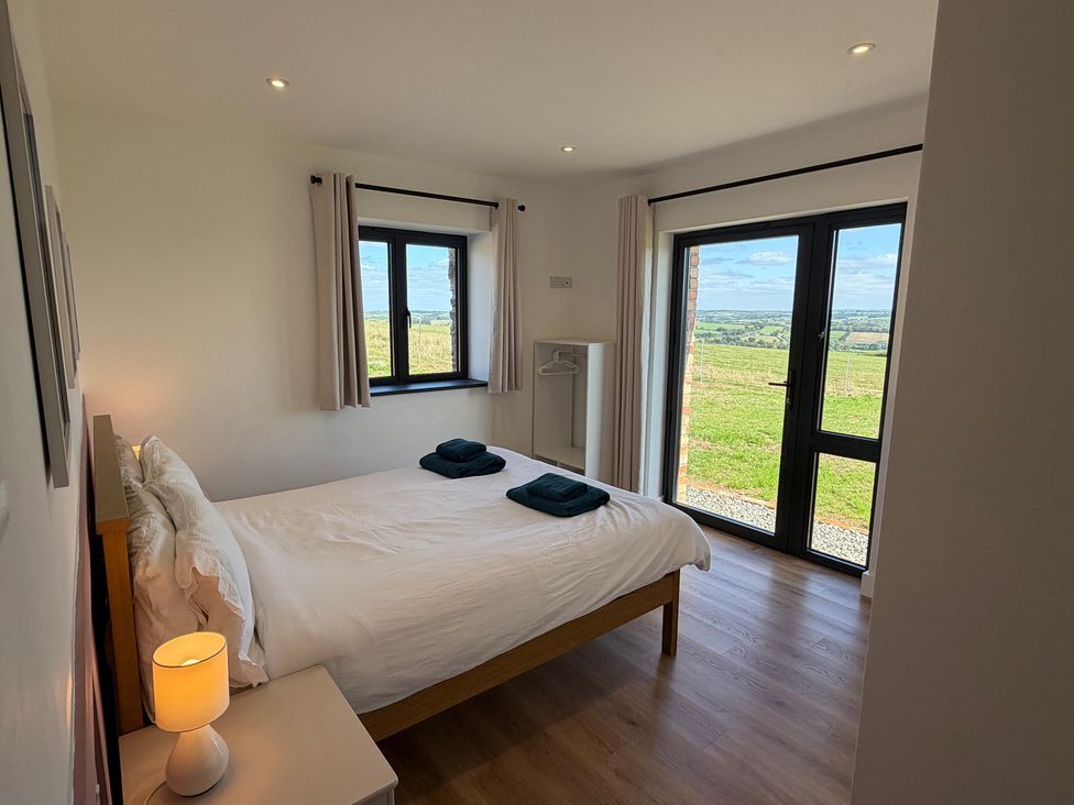 A bedroom with a bed and windows at High View Barn in Launceston
