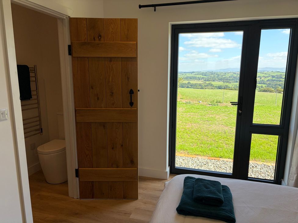 A bedroom with a window and wooden door at High View Barn in Launceston