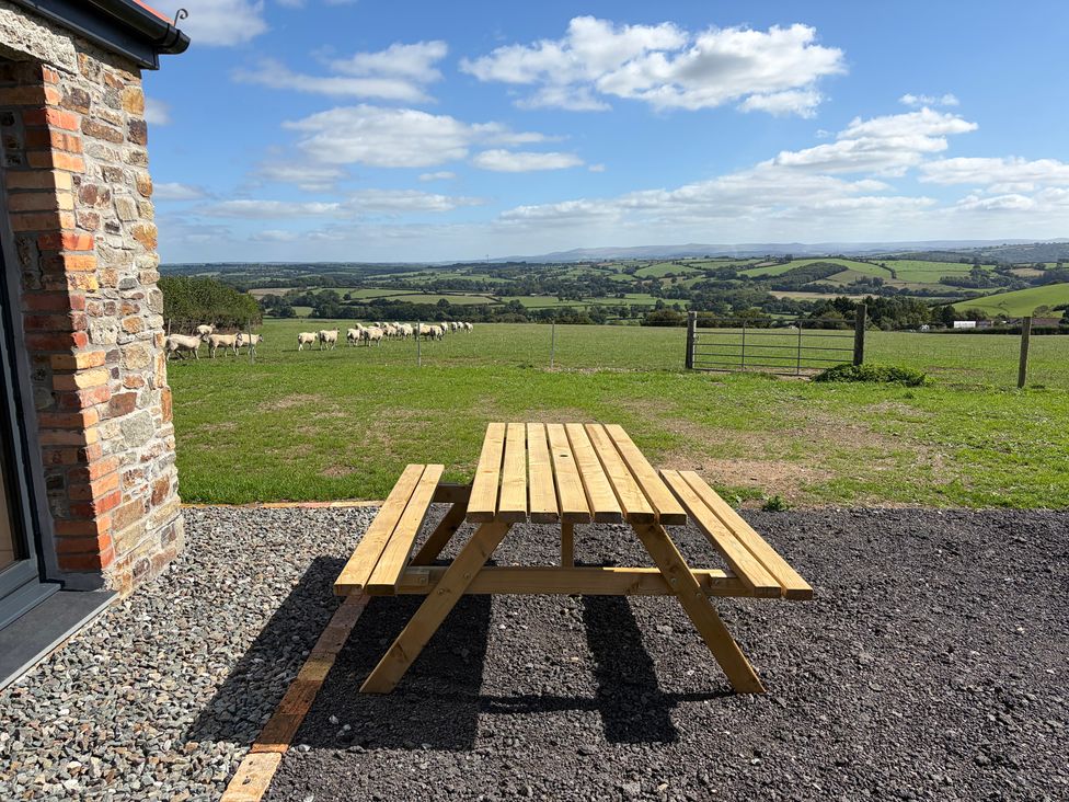 A picnic table overlooking a field with sheep at High View Barn in Launceston