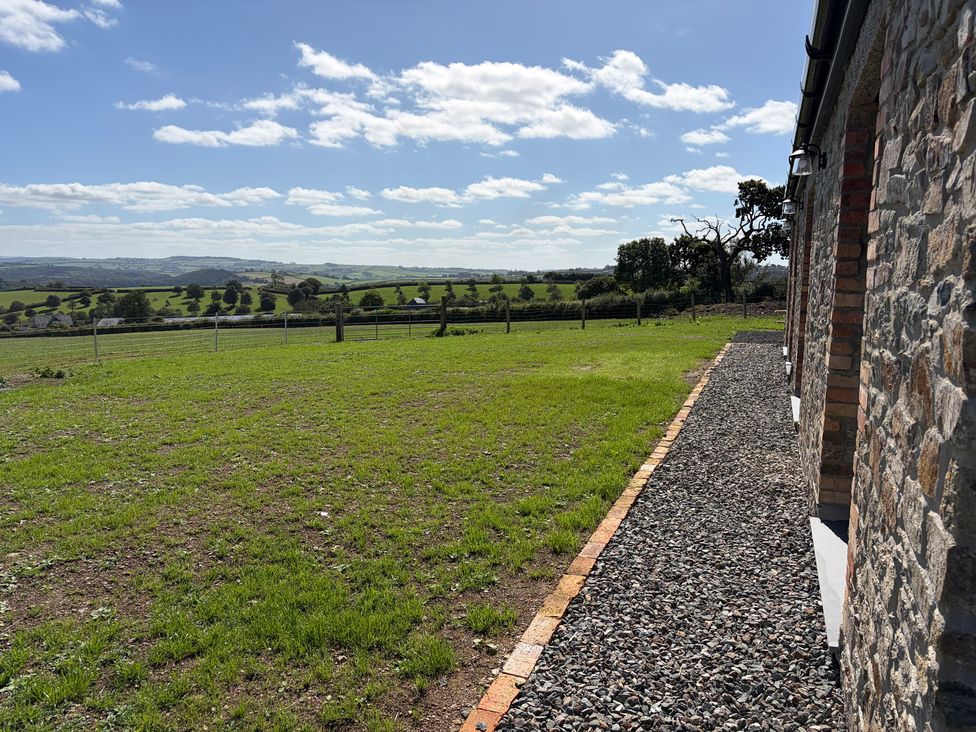 A grassy outdoor area with a gravel path and stone wall at High View Barn Launceston