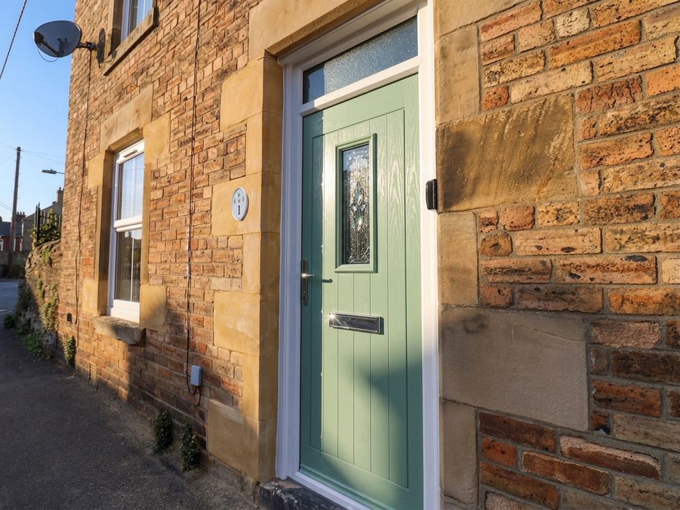 A front door with a window and brick wall at Corner House Wark