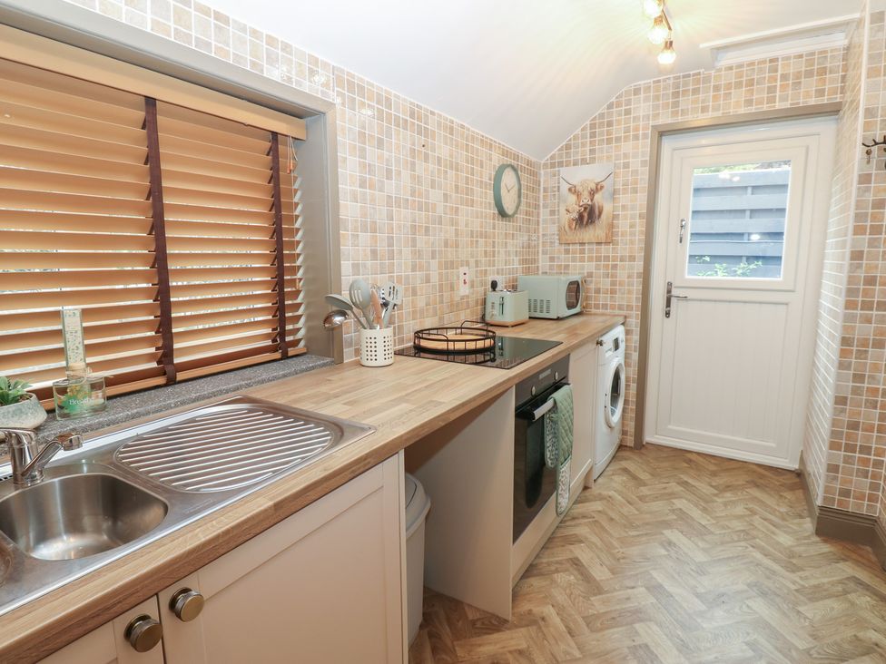 A kitchen featuring a sink, washing machine, and microwave at Corner House in Wark