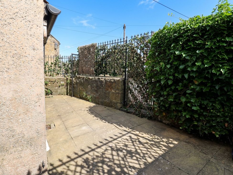 A garden with a paved pathway and a fence at Corner House in Wark